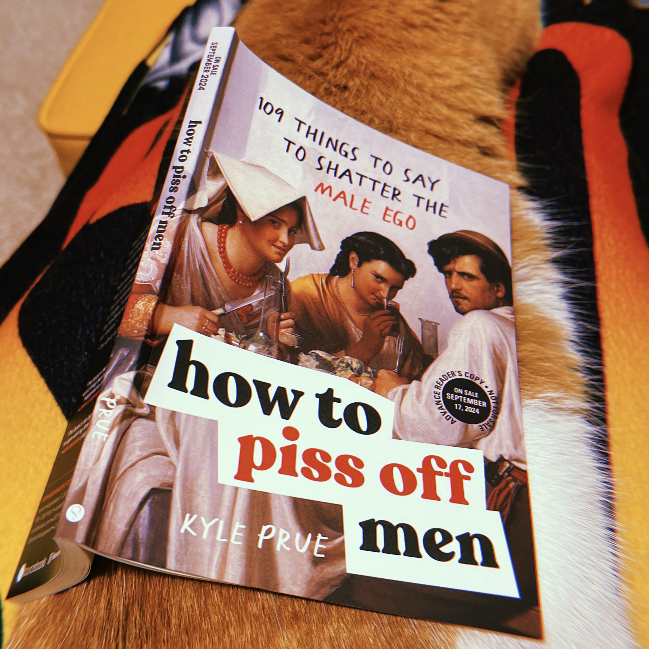 A book propped up on a cat's back.